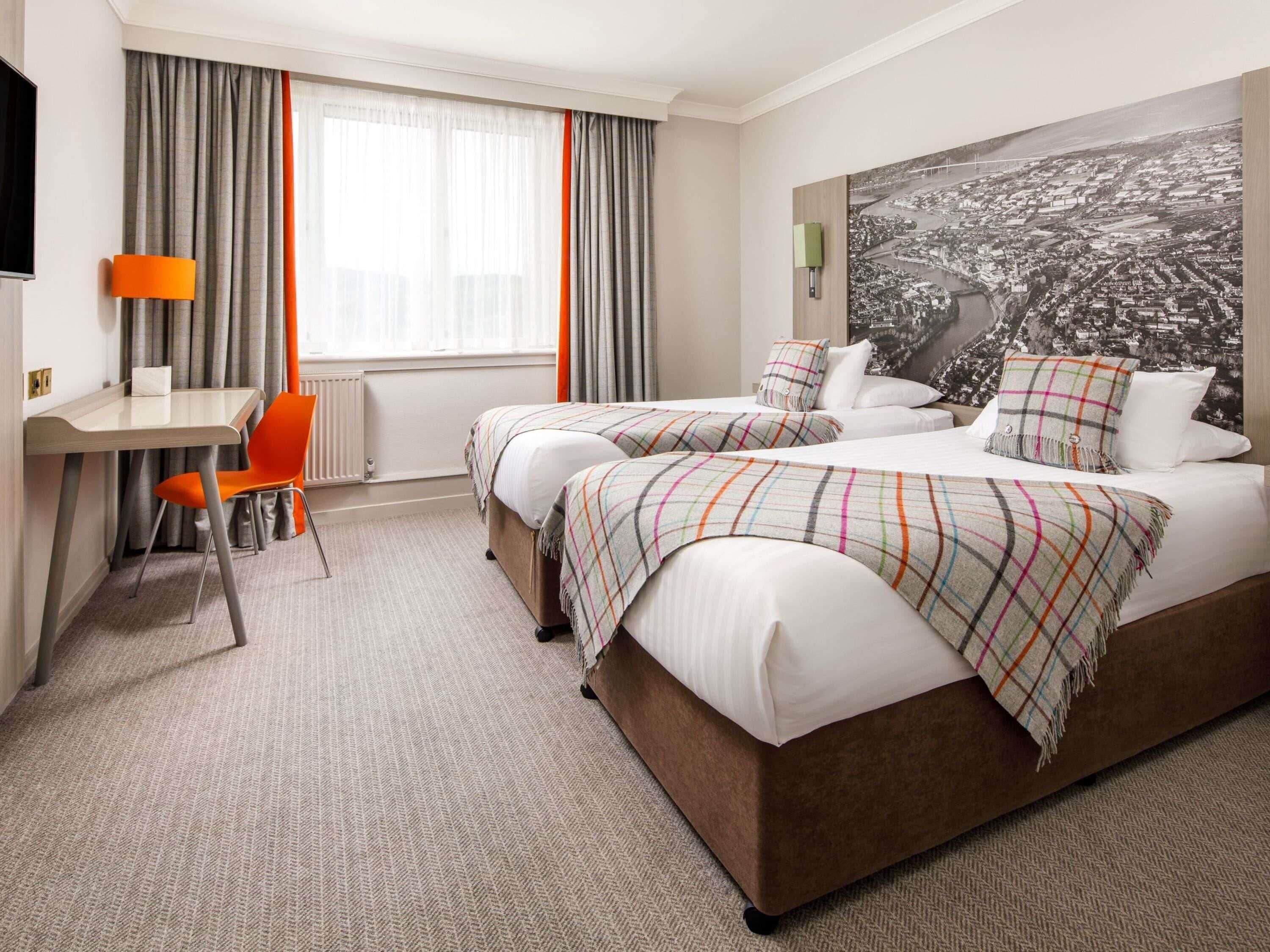 Habitación de hotel con dos camas, un escritorio y una silla.