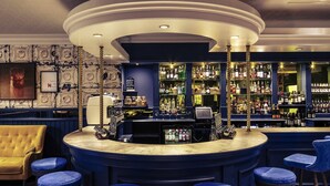 A bar area with a curved counter, bar stools, and a variety of liquor bottles. - Mercure Inverness Hotel (Inverness)