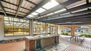 A covered outdoor area with a brick counter, seating, and large windows.