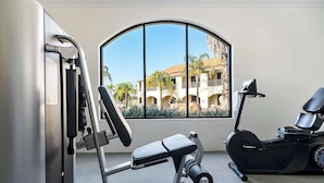 A gym with exercise equipment, a window with a view of buildings, and a treadmill.