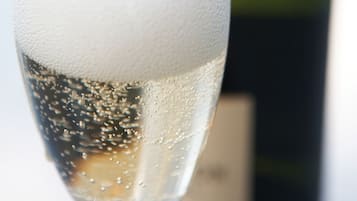 A glass of champagne with bubbles, and a blurred bottle in the background.