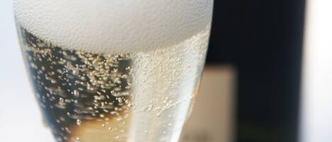 A glass of champagne with bubbles, and a blurred bottle in the background.