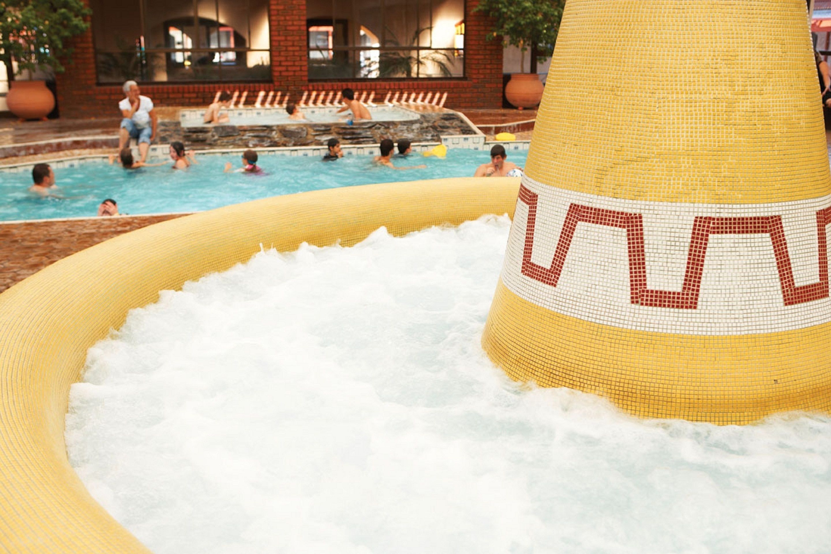Un espace piscine doté d’une grande structure gonflable jaune et d’un jacuzzi.