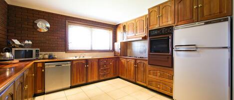 A kitchen with wooden cabinets, a stainless steel refrigerator, a microwave, and a dishwasher.