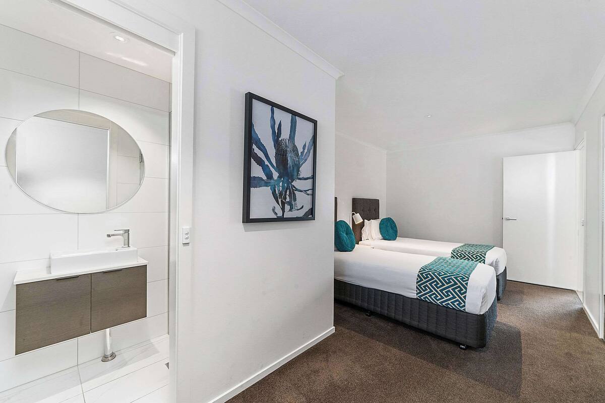 A modern bathroom with a round mirror, a white sink, and a framed artwork on the wall.