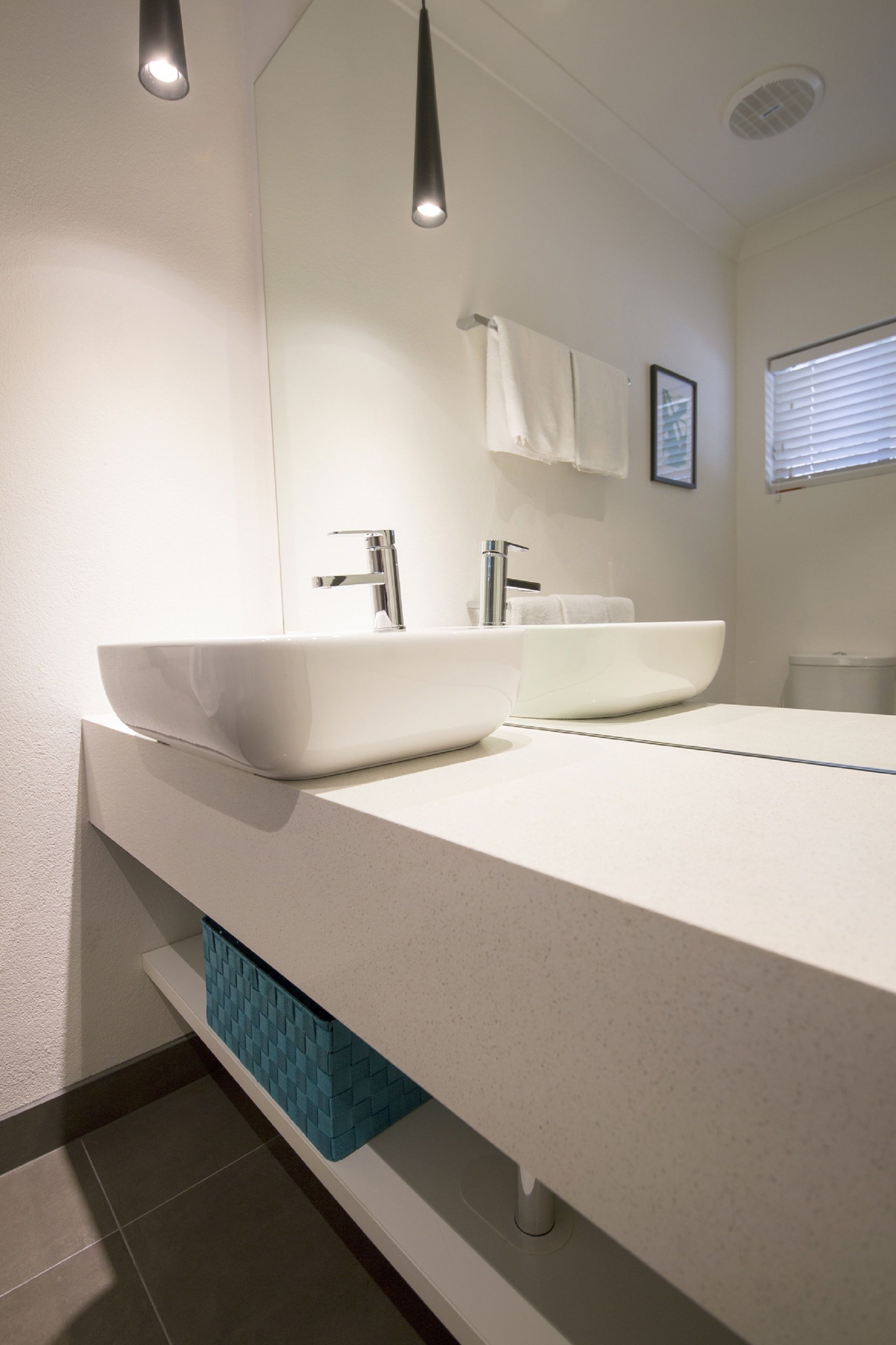 A modern bathroom with two vessel sinks, a large mirror, and a towel rack.
