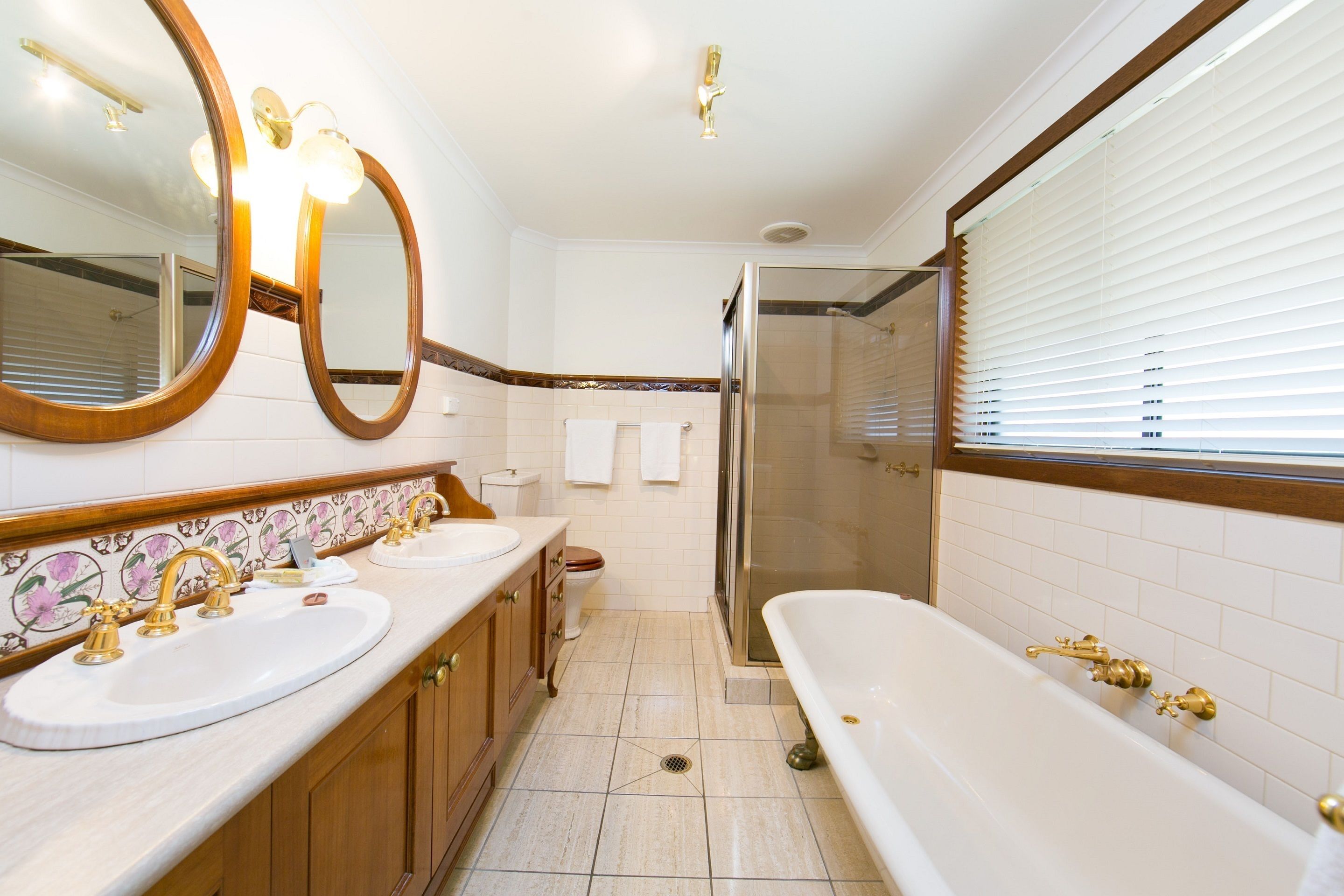 Une salle de bain avec un grand miroir, deux lavabos, une baignoire et une douche.