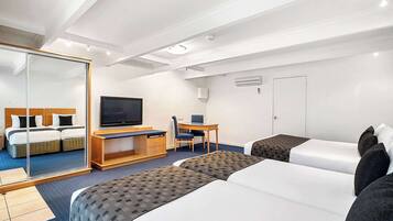A hotel room with two beds, a desk with a chair, a television, and a wardrobe.