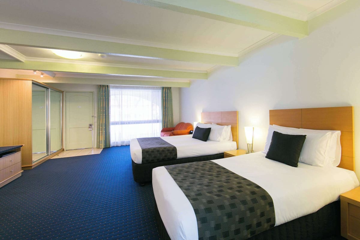 A hotel room with two beds, a desk, and a wardrobe.