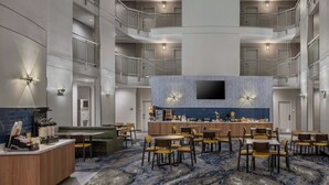 A hotel lobby with a central bar, multiple dining tables, and a high ceiling with balconies. - Fairfield Inn & Suites by Marriott Oakland Hayward (Hayward)