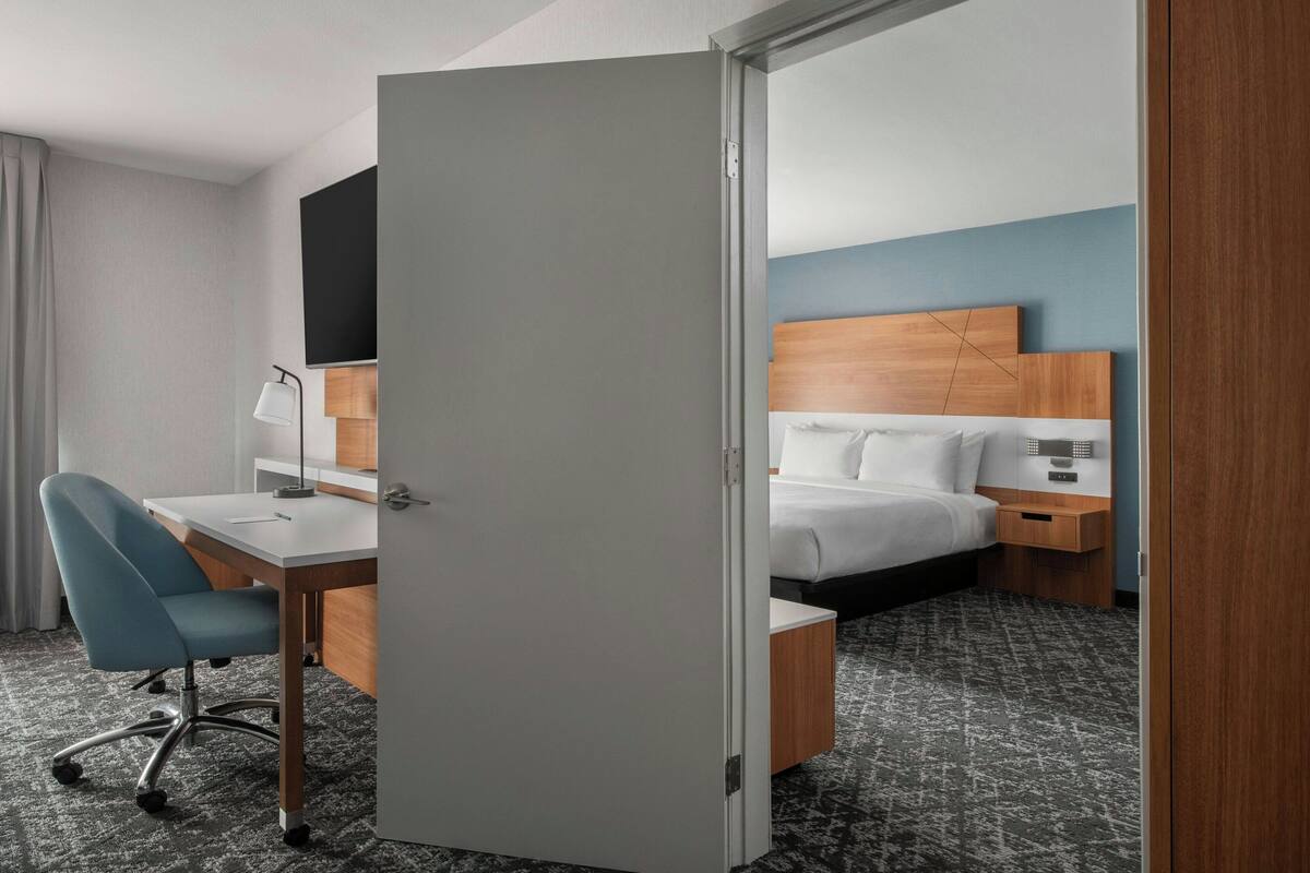 Ein Hotelzimmer mit Schreibtisch, Stuhl, Bett und Nachttisch.