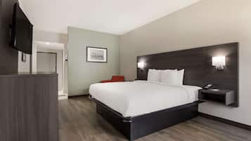A modern hotel room with a large bed, a bedside table with a phone, a wall-mounted TV, and a framed picture on the wall.