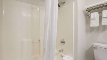 A bathroom with a shower, toilet, and a towel rack with towels.
