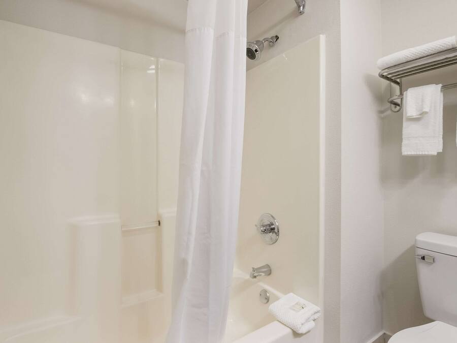 A bathroom with a shower, toilet, and a towel rack with towels.
