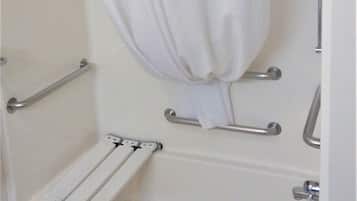A standard bathroom with a bathtub, shower, and grab bars.