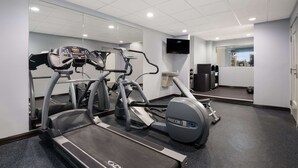 Un gimnasio con cintas de correr, elípticas y una bicicleta estática.