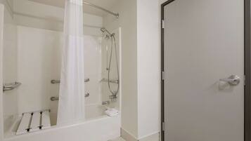 A modern bathroom with a bathtub, shower, and a door.