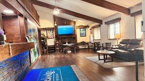 A spacious living area with a fireplace, a flat-screen TV, and a seating area with a leather couch and chairs. - Travelodge by Wyndham Valleyfair Shakopee (Shakopee)