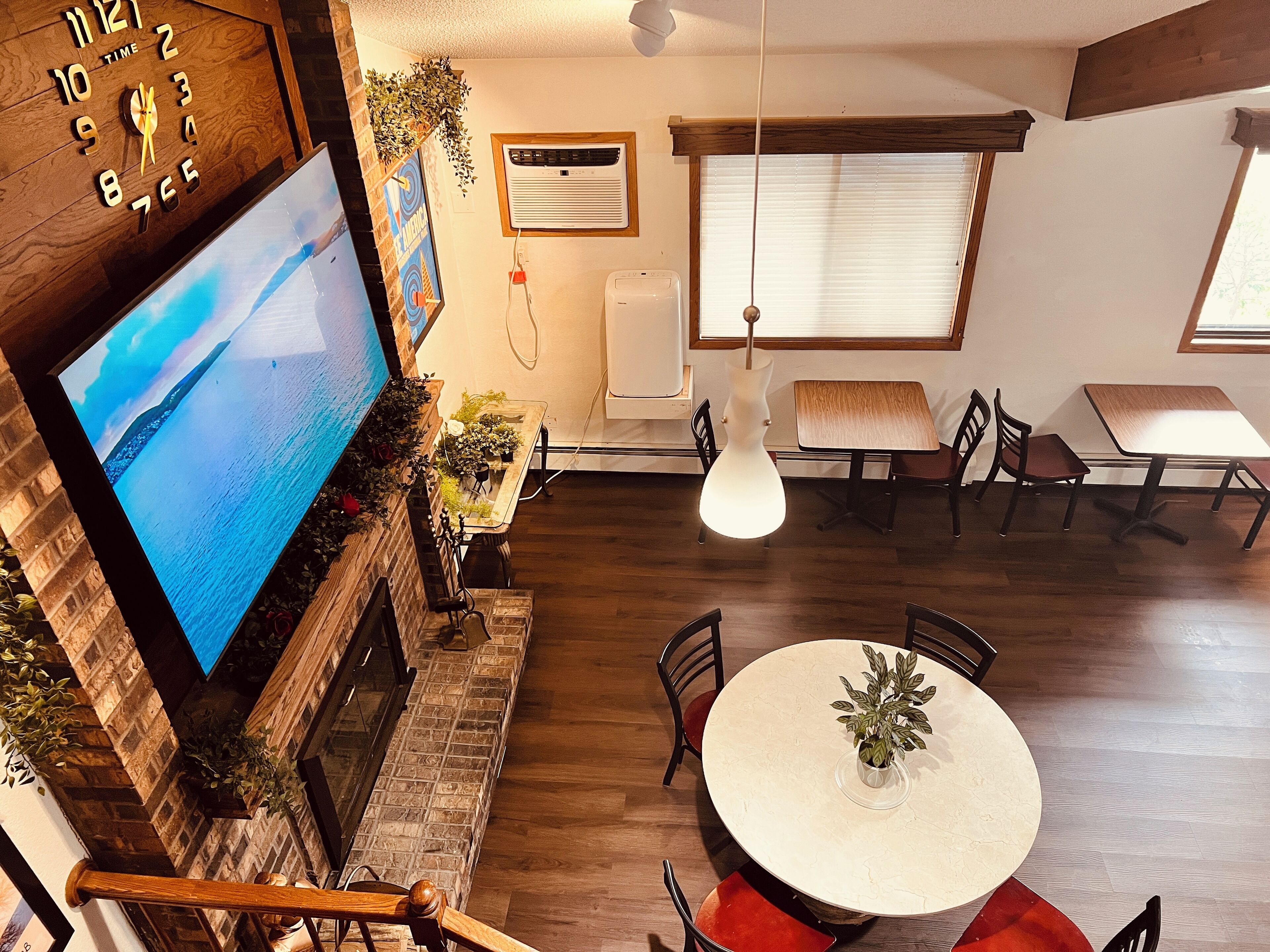 A modern living room with a large flat-screen TV, a fireplace, and a dining area with a round table and chairs.