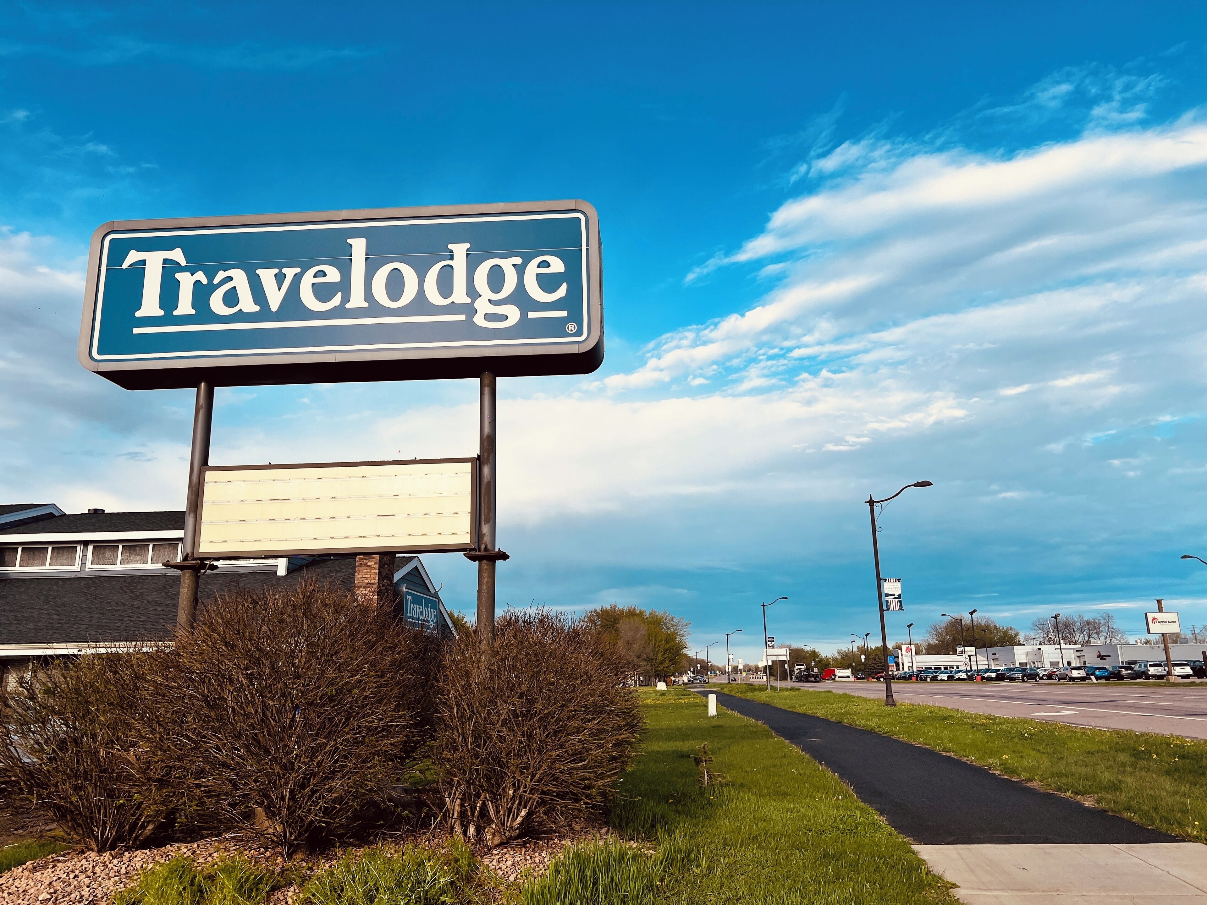 A Travelodge sign with a clear view of the surrounding area, including a road and some buildings in the background.