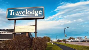 A Travelodge sign with a clear view of the surrounding area, including a road and some buildings in the background.
