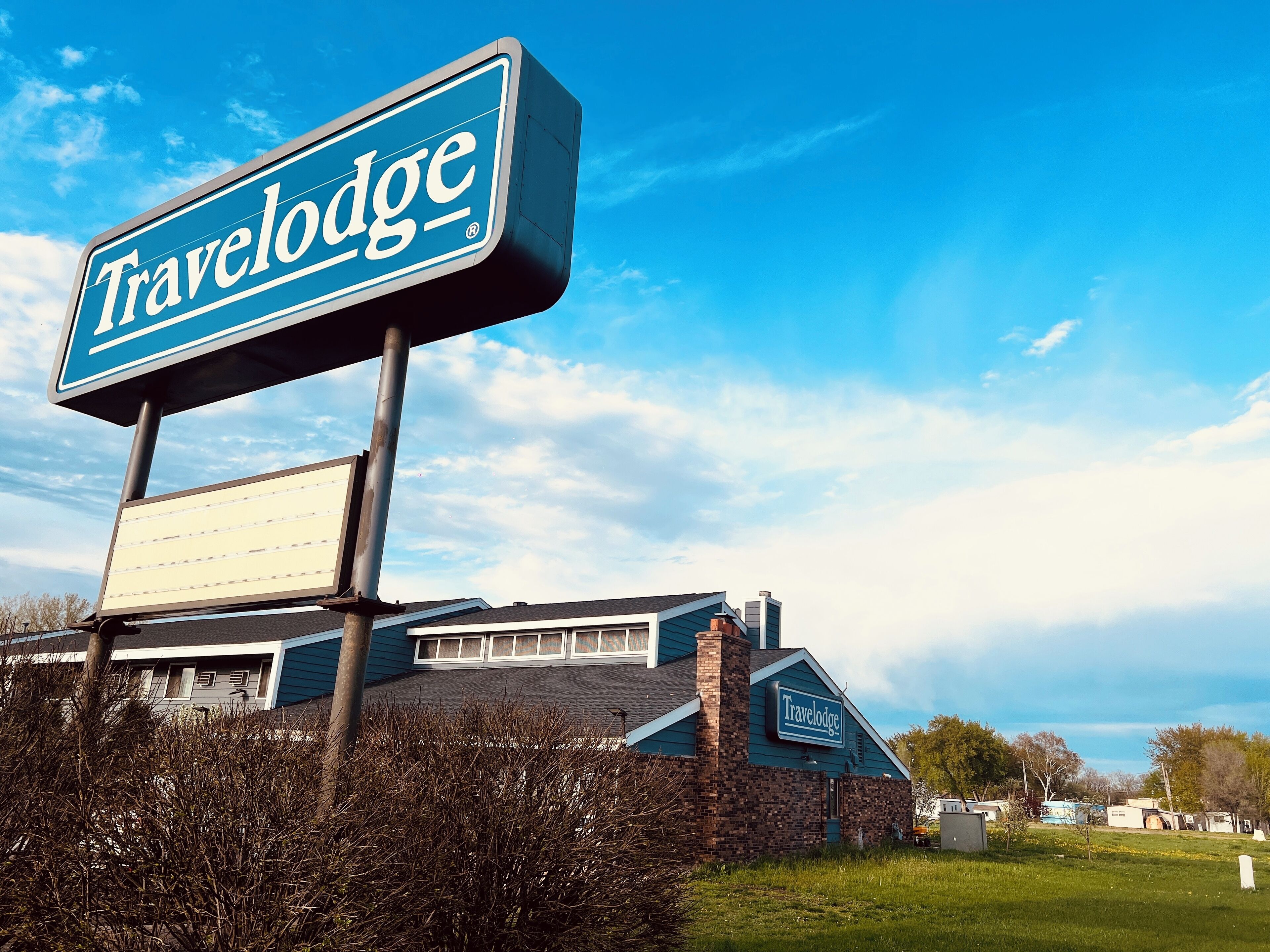 Une enseigne et un bâtiment de la chaîne Travelodge, avec une façade en briques et une grande pelouse devant.