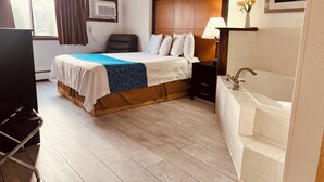 A hotel room with a bed, a chair, a desk, a lamp, a sink, and a window with curtains. - Travelodge by Wyndham Valleyfair Shakopee (Shakopee)