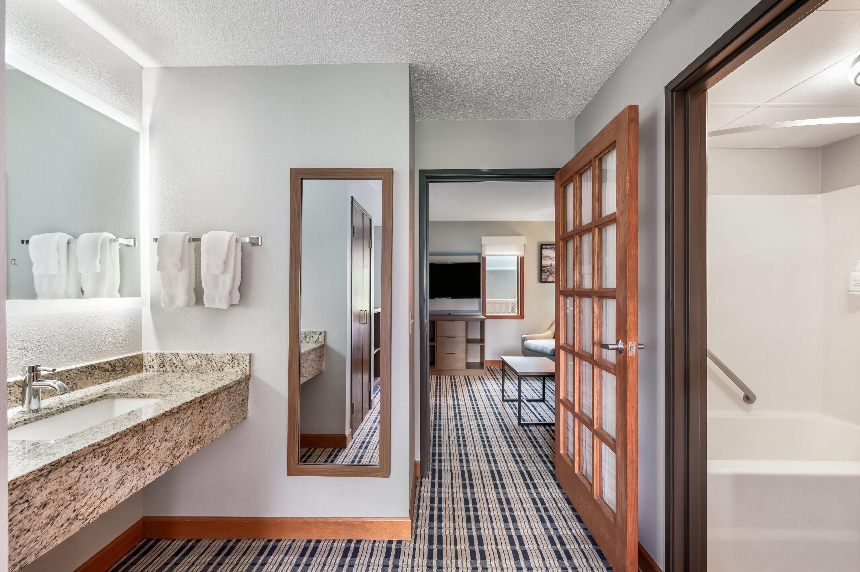 Un baño de hotel con lavamanos, espejo y perchero para toallas.