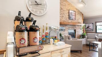 A coffee station with espresso machines, a clock, and a fireplace in a lounge area.