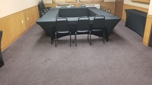 Una sala de conferències amb una taula llarga, sis cadires i dues finestres amb persianes.