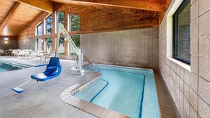 An indoor swimming pool with a slide, wooden ceiling, and tiled walls. - AmericInn by Wyndham Hutchinson (Hutchinson)