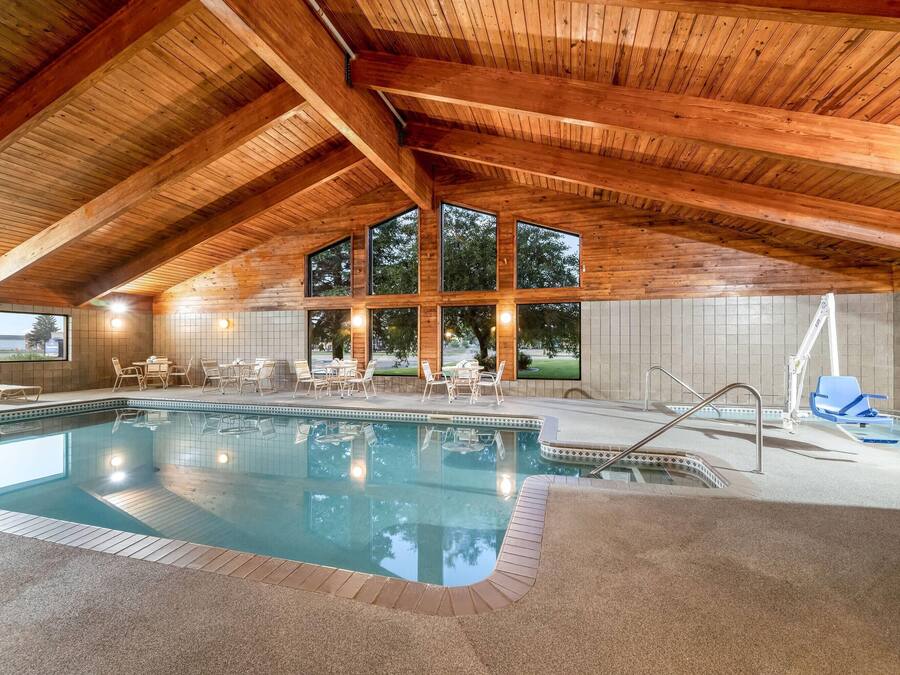 An indoor swimming pool with a wooden ceiling and large windows.