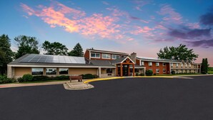 A hotel with a large parking lot, a covered entrance, and a building with multiple windows. - AmericInn by Wyndham Hutchinson (Hutchinson)