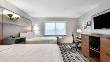 A hotel room with two beds, a desk, a chair, a television, and a window with a view.