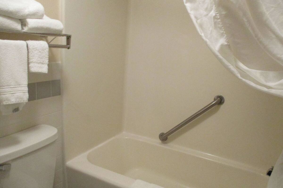 Un baño con bañera, inodoro y toallero con toallas dobladas.