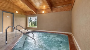 An indoor swimming pool with a wooden ceiling, a window with a view of trees, and a sign indicating a women's restroom.