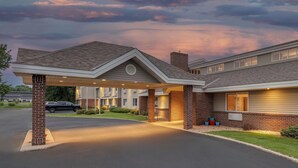 A hotel with a covered entrance, brick facade, and a parking lot.