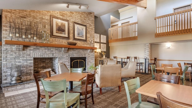 A cozy restaurant with a brick fireplace, wooden beams, and a mezzanine with a balcony.
