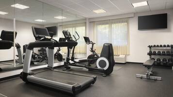 A gym with treadmills, elliptical machines, and a bench.