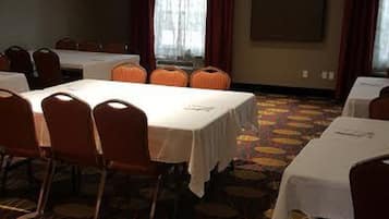 A conference room with round tables and chairs, a patterned carpet, and a large window with curtains.
