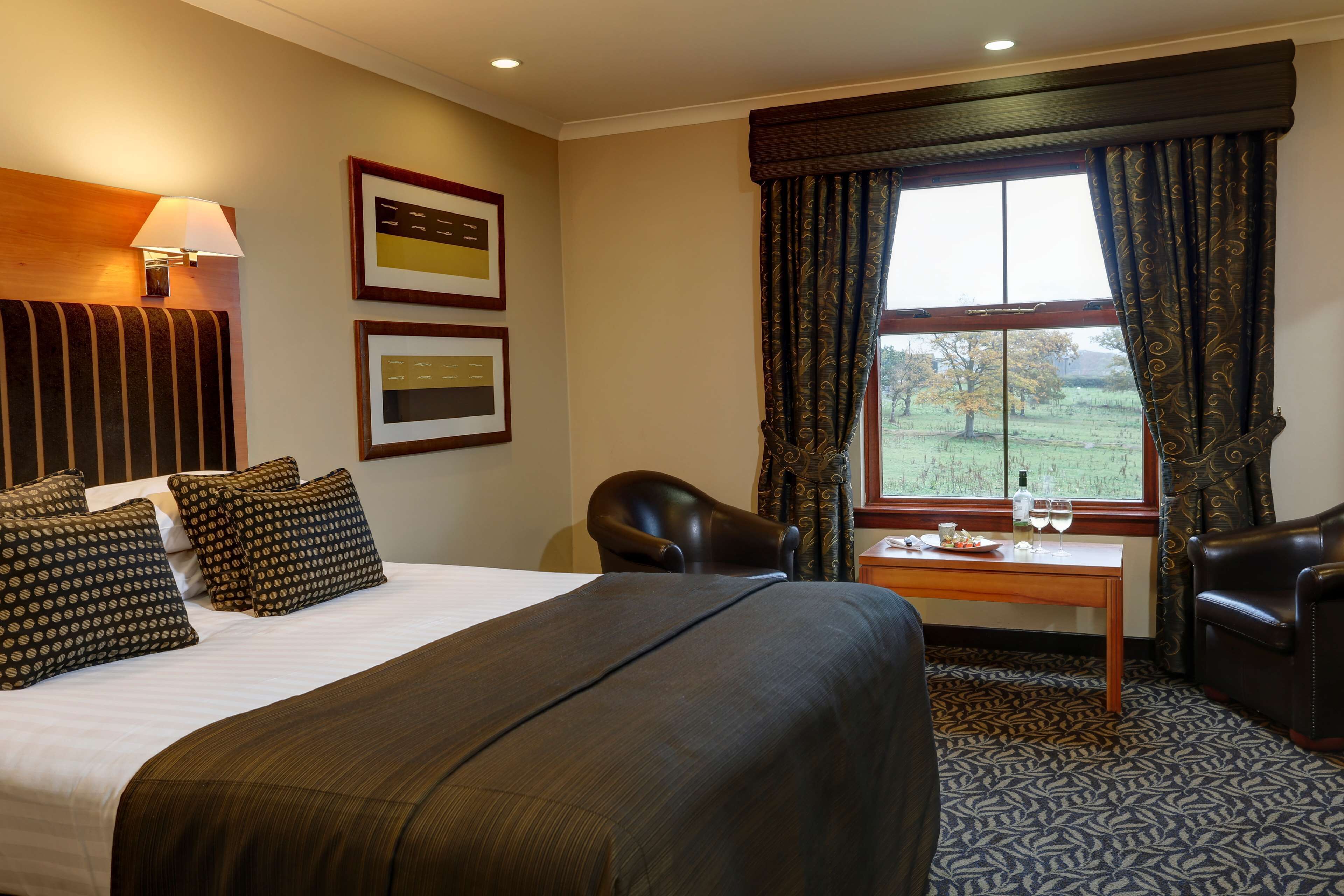 Een hotelkamer met een groot bed, een bureau, een stoel en een raam met gordijnen.