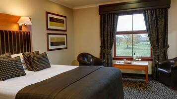 Een hotelkamer met een groot bed, een bureau, een stoel en een raam met gordijnen.