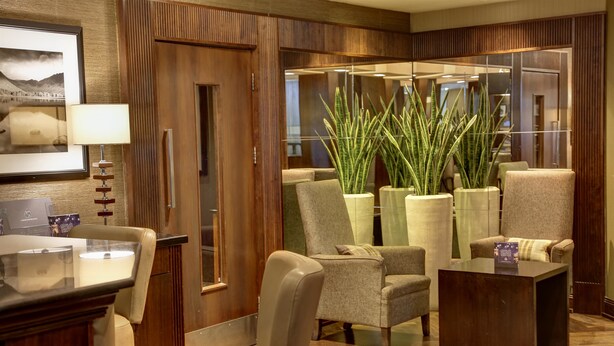 A hotel lobby with a wooden reception desk, leather chairs, a coffee table, and large potted plants. - Best Western Garfield House Hotel (Glasgow)