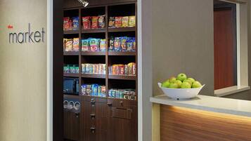 A kitchen area with a pantry stocked with various food items and a bowl of green apples on the counter.