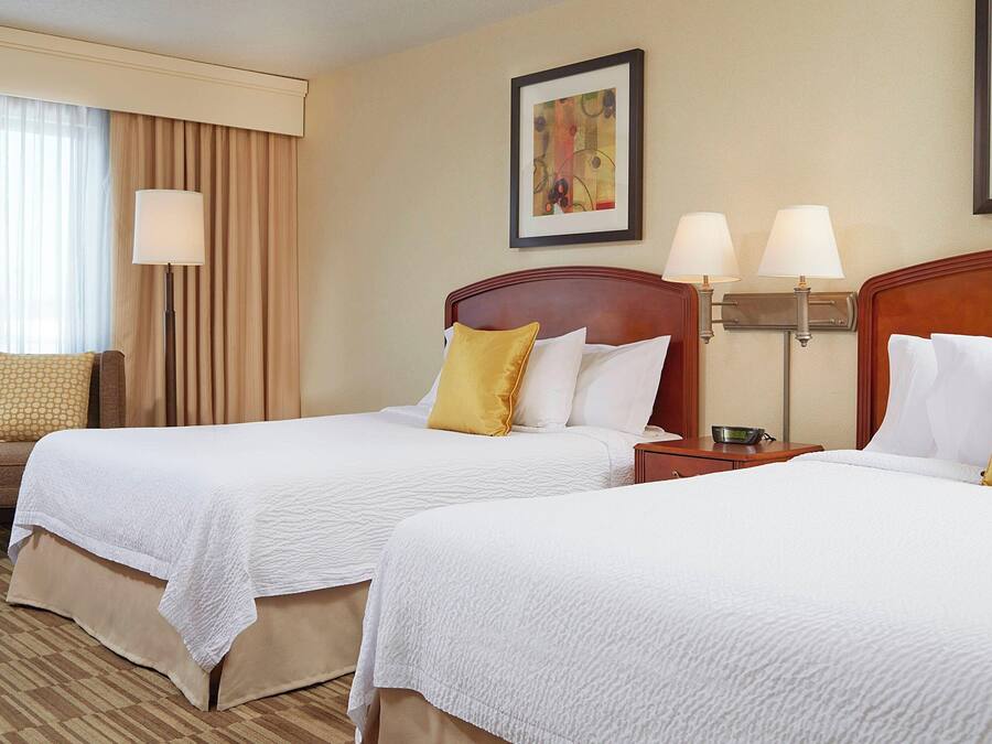 A hotel room with two beds, a sofa, a lamp, and a painting on the wall.