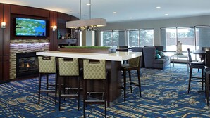 A modern bar area with a large TV, a fireplace, and a patterned carpet.