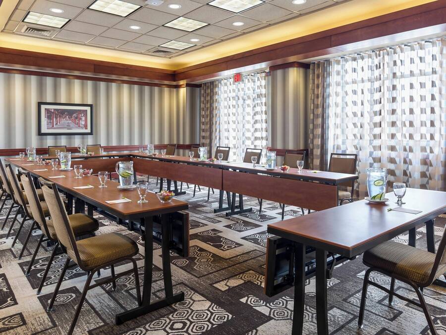 A conference room with long tables, chairs, and a patterned carpet.