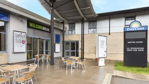 A hotel exterior with a 'Welcome Break' sign, outdoor seating area, and a 'Days Inn' sign advertising meeting rooms and U.K. reservations. - Days Inn by Wyndham Donington A50 (Derby)