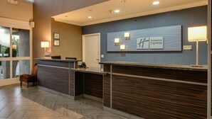 A reception area with a modern design, featuring a reception desk, a large wall-mounted sign, and a seating area with a chair.