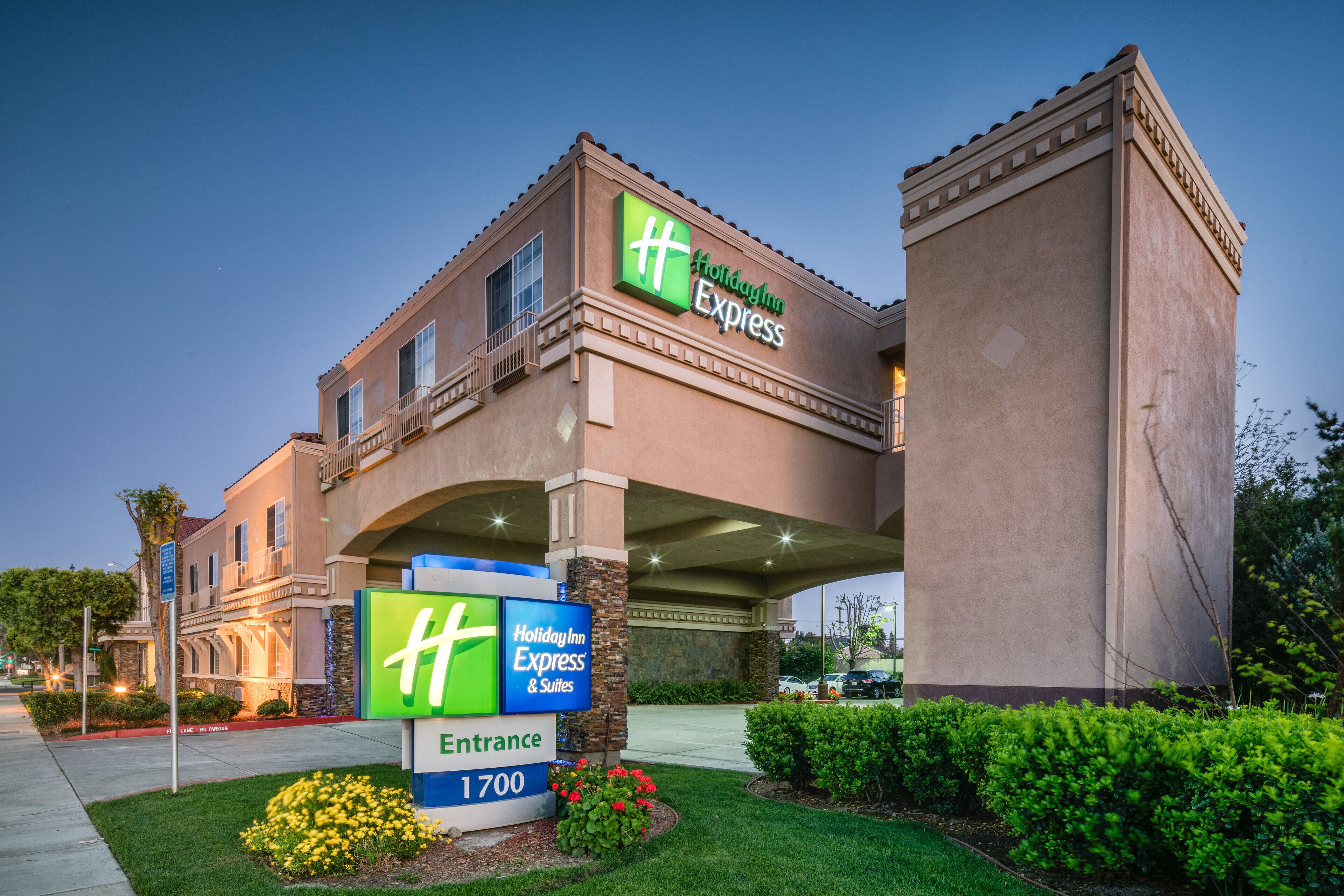 Een Holiday Inn Express gebouw met een herkenbaar entreebord, een parkeerplaats en verzorgd groen.